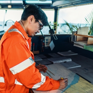 An Officer on the bridge of a ship plots position on a nautical chart